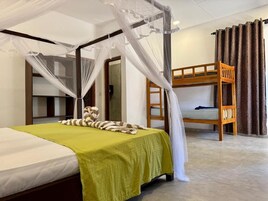 Una habitación con una cama, una litera, una silla de madera y una mosquitera.