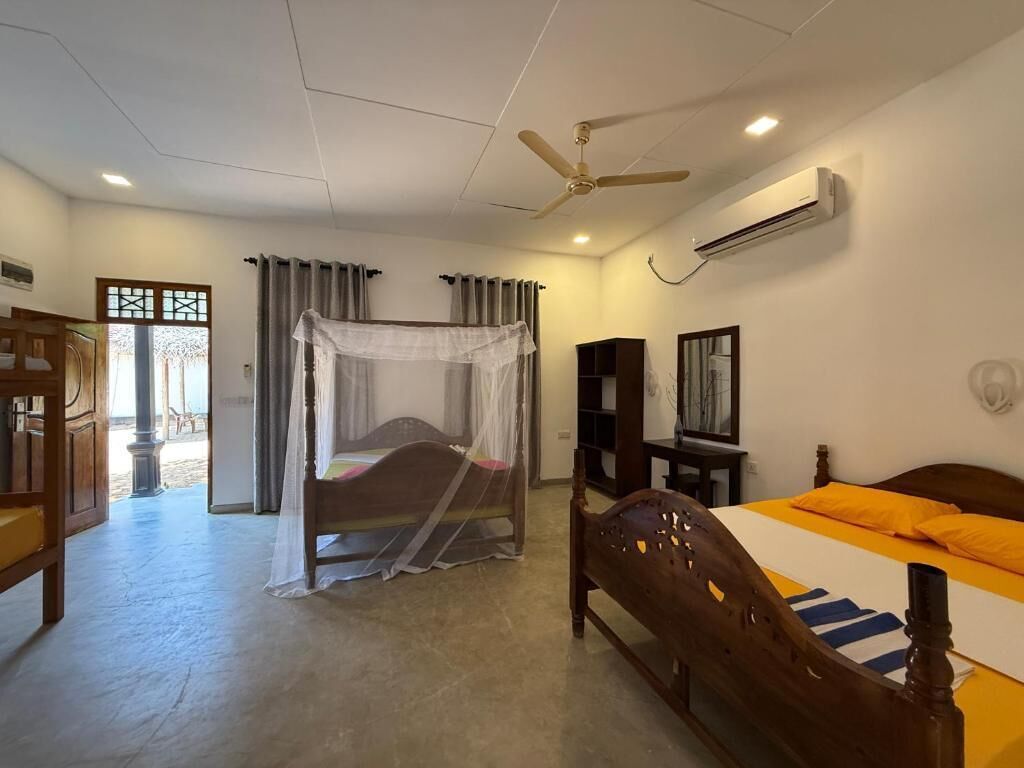 A bedroom with a bed, a ceiling fan, an air conditioning unit, a bedside table, and a wardrobe.