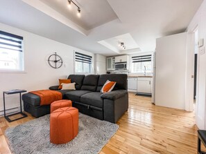 A modern living room with a sectional sofa, ottomans, and a grey rug.