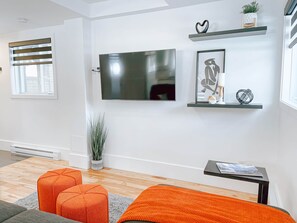 A modern living room with a flat-screen TV, a sofa, a coffee table, and decorative items on shelves. - Le Champery Tremblant 5 (Mont-Tremblant)