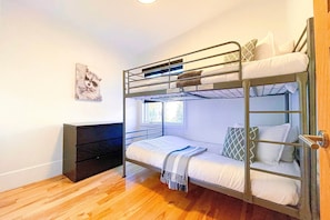 A bunk bed room with a wooden floor, a desk, and a window. - Le Champery Tremblant 4 (Mont-Tremblant)
