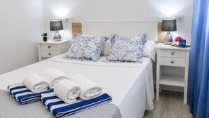 A hotel room with a bed, two bedside tables, a nightstand, a lamp, a plant, and a blue curtain. - Sun and Beach in La Mata (Torrevieja)