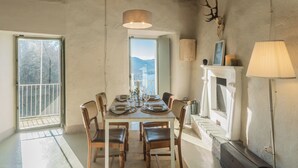 Un comedor con una mesa dispuesta para seis comensales, una araña, una chimenea y un cráneo de ciervo en la pared.