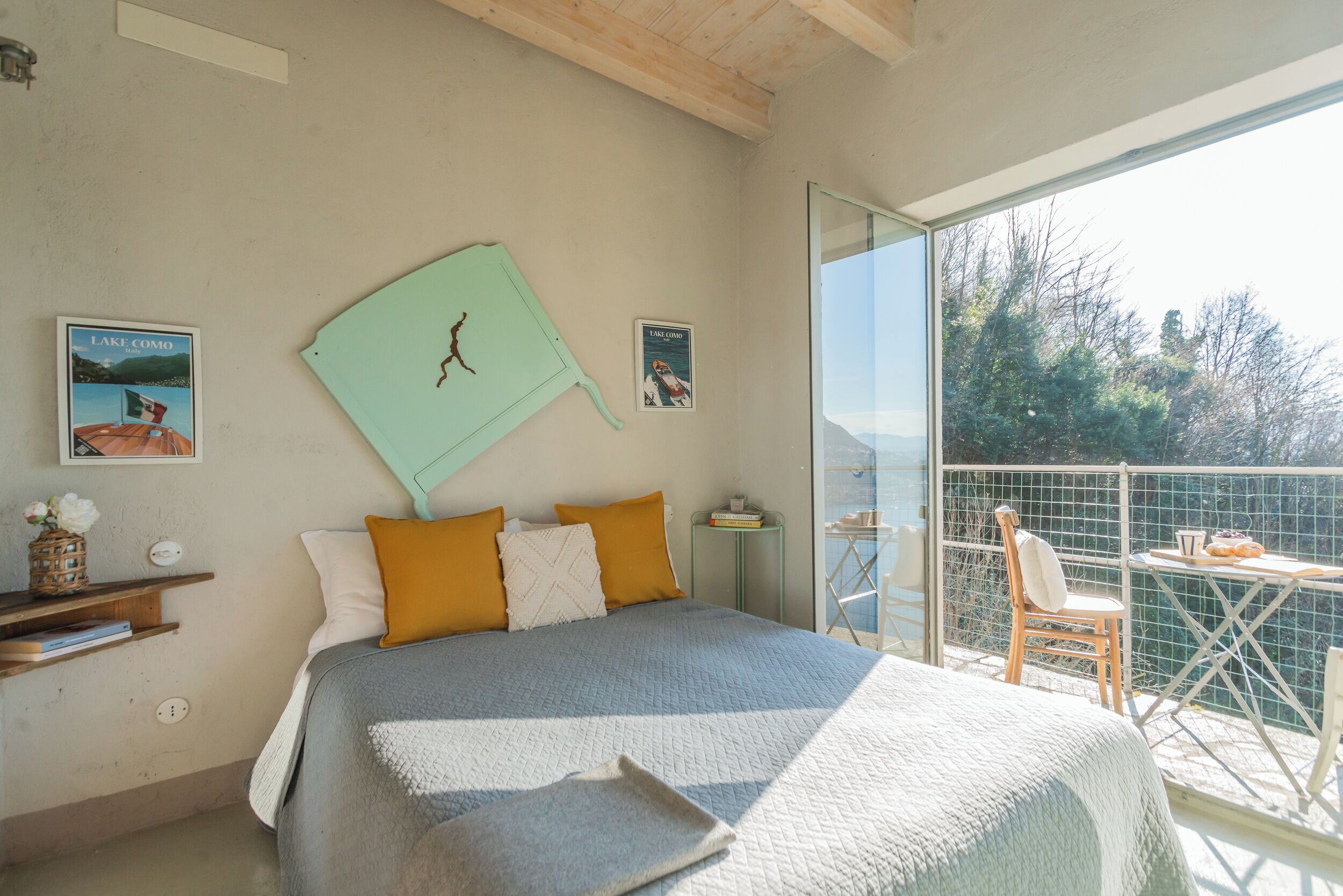 Une chambre avec un lit, une fenêtre, un balcon et une vue sur les arbres.