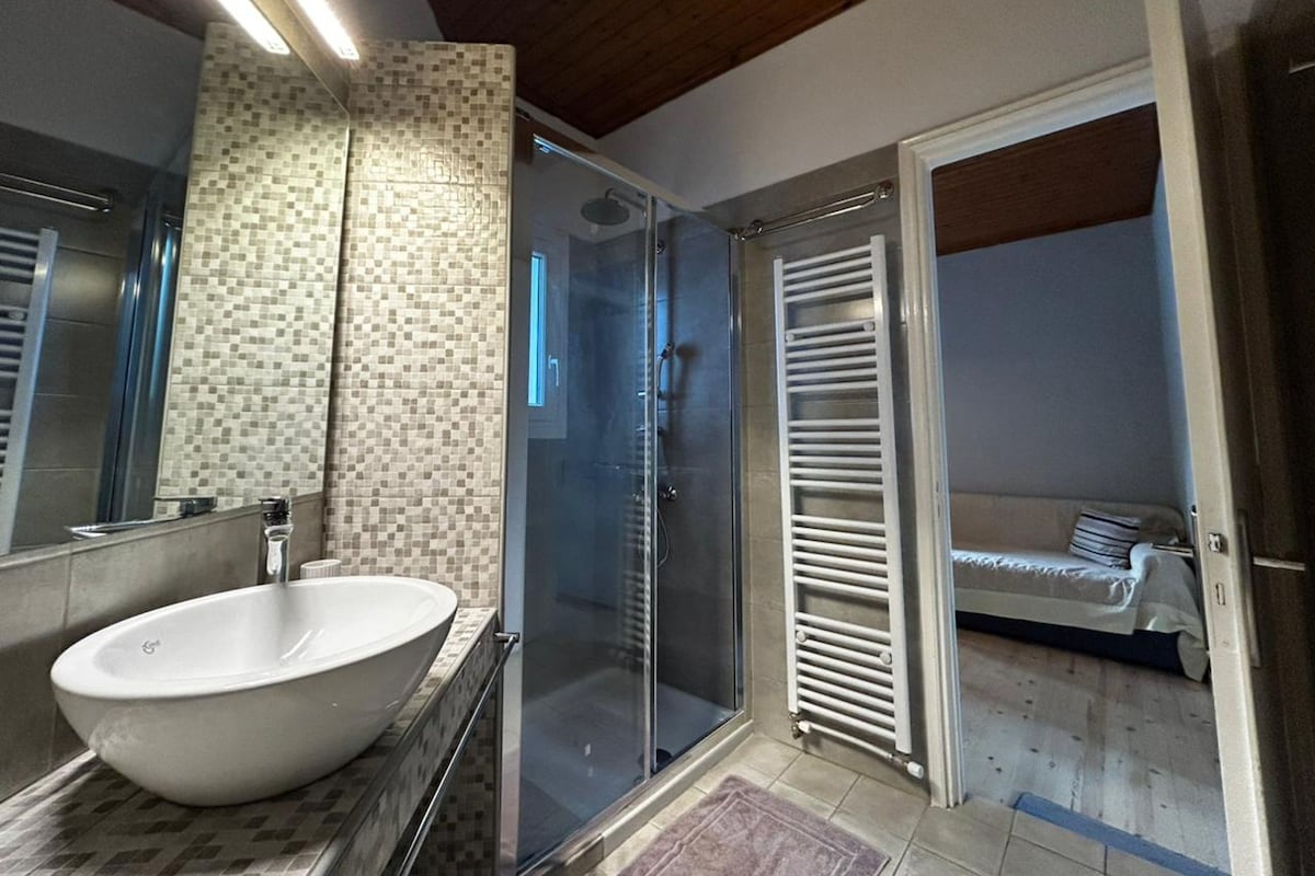 A modern bathroom with a large white sink, a glass shower enclosure, and a walk-in shower.