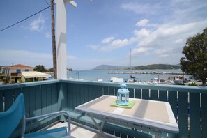 A balcony with a table and chair, overlooking a marina with boats and a hilly landscape. - Tsonas Apartments (Lefkada)