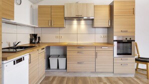 Een moderne keuken met houten kastjes, een inbouwoven en een vaatwasser.