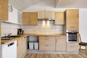 A modern kitchen with wooden cabinets, a built-in oven, and a dishwasher. - Apartment 'Af' with Shared Garden, Balcony and Wi-Fi (Bonndorf im Schwarzwald)