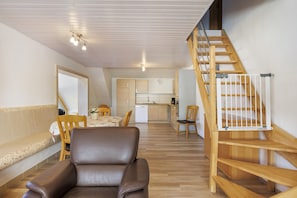A modern interior with a dining area, kitchen, and a wooden staircase. - Apartment 'Af' with Shared Garden, Balcony and Wi-Fi (Bonndorf im Schwarzwald)