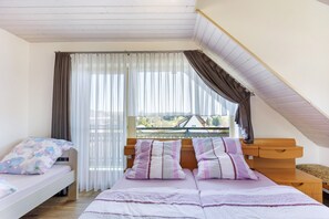 A bedroom with a loft bed, a bedside table, and a window with curtains. - Apartment 'Af' with Shared Garden, Balcony and Wi-Fi (Bonndorf im Schwarzwald)