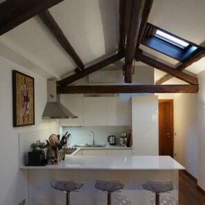 A modern kitchen with a central island, wooden beams, and a skylight. - Stylish Penthouse in Venice Lido with Amazing views, central and close to beach! (Lido)