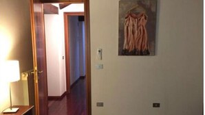 Ein Hotelzimmer mit einem Bett, einem Nachttisch, einem Bild an der Wand und einer Tür zu einem weiteren Raum.
