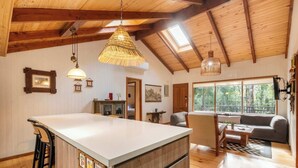 A spacious kitchen with a large island, wooden beams, and a high ceiling. - Rincón Nativo 3D y Piscina (Pucón)
