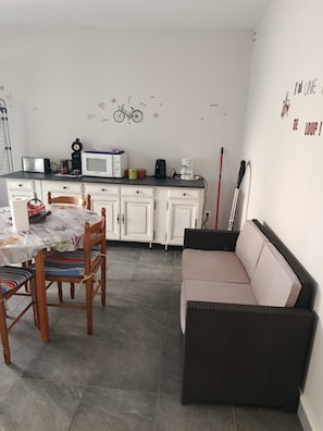 Un espacio habitable pequeño con kitchenette, mesa de comedor y sofá.