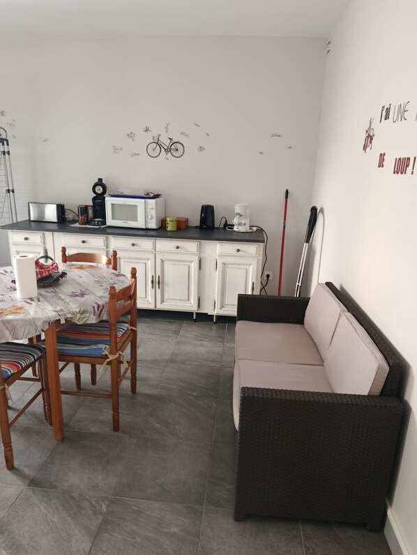 Un espace de vie compact comprenant un coin cuisine, une table à manger et un canapé.