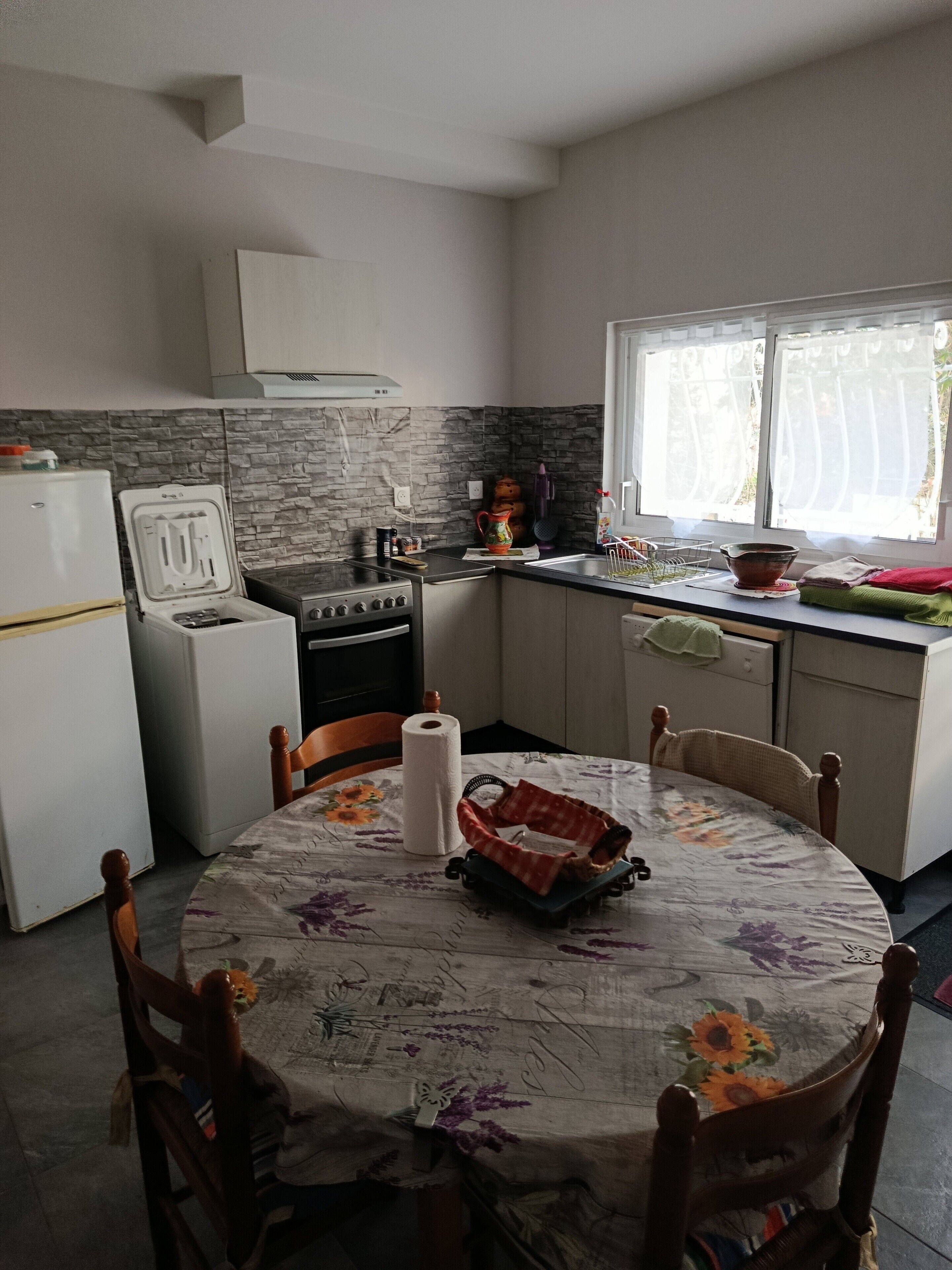 Une cuisine équipée d’une cuisinière, d’un réfrigérateur et d’une table à manger avec des chaises.