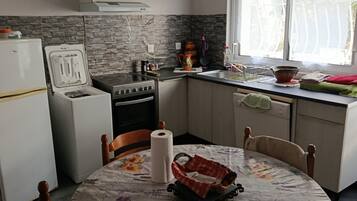 Une cuisine équipée d’une cuisinière, d’un réfrigérateur et d’une table à manger avec des chaises.