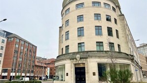Ein historisches Gebäude mit einer gewölbten Fassade, zahlreichen Fenstern und einem zentralen Eingang.