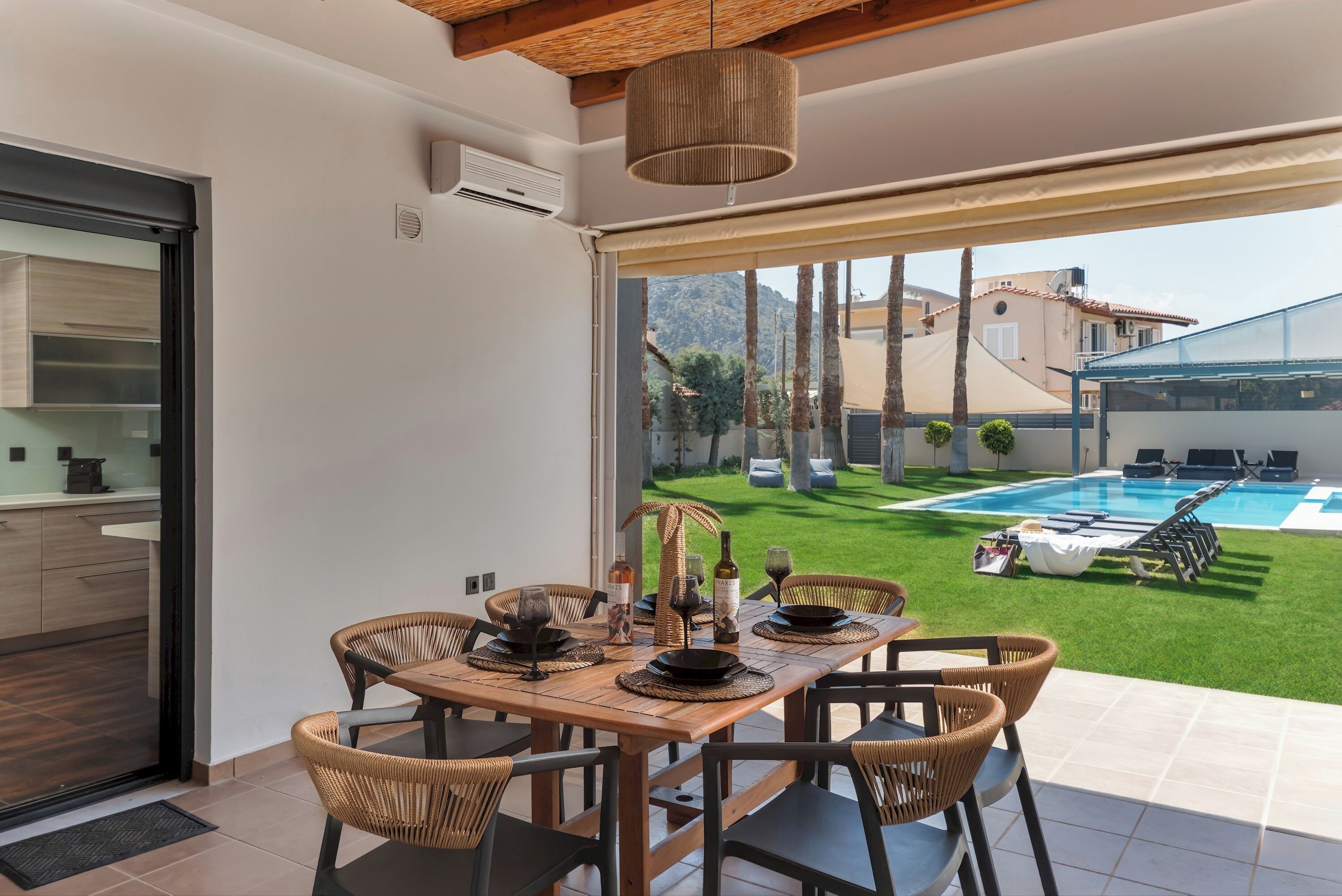 Un coin repas avec une table dressée pour quatre personnes, une vue sur une piscine et un balcon offrant une vue sur la piscine et les bâtiments environnants.