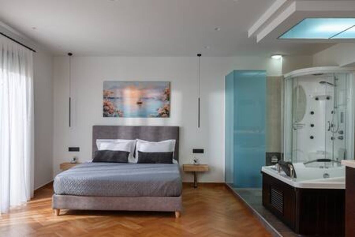 A modern bedroom with a large bed, a glass-enclosed shower, and a painting on the wall.