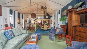A spacious living room with a high ceiling, a chandelier, and a variety of seating options including a sofa, armchairs, and ottomans. - The Church House Spacious Heritage Escape for Two (North Hobart)