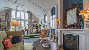 A cozy living room with a fireplace, a sofa, a coffee table with books, and a large mirror. - The Church House Spacious Heritage Escape for Two (North Hobart)