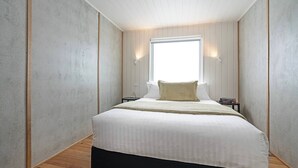 Une chambre à coucher avec un grand lit, une fenêtre et une table de chevet.