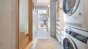 Une buanderie équipée d’un lave-linge à chargement frontal, d’un étendoir et d’une petite table avec des chaises.