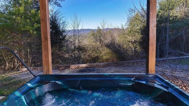 Un bain à remous offrant une vue dégagée sur un paysage boisé et sur des collines lointaines.