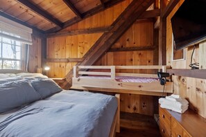 Eine Holzhütte mit Etagenbetten, einem Fernseher und einem Fenster.