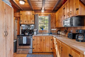 Una cocina con gabinetes de madera, estufa, microondas y cafetera.