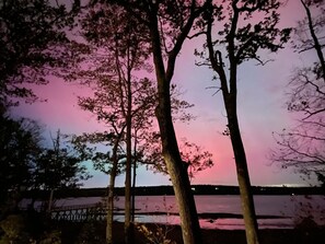 A nighttime view of a bridge over a body of water with trees silhouetted against a pink sky.