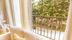 A balcony with a metal railing, a beige sofa with a patterned cushion, and a view of trees and a street. - *Modern apartment* near Antigua Guatemala (Santo Tomas Milpas Altas)