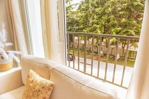 A balcony with a metal railing, a beige sofa with a patterned cushion, and a view of trees and a street. - *Modern apartment* near Antigua Guatemala (Santo Tomas Milpas Altas)