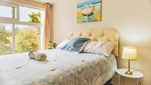 A bedroom with a large bed, a painting of a boat on the wall, and a window with curtains. - *Modern apartment* near Antigua Guatemala (Santo Tomas Milpas Altas)