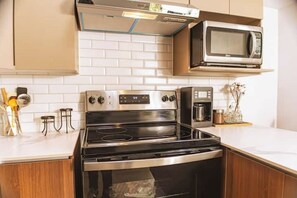 A kitchen with a stainless steel stove, a microwave, and a coffee maker. - *Modern apartment* near Antigua Guatemala (Santo Tomas Milpas Altas)