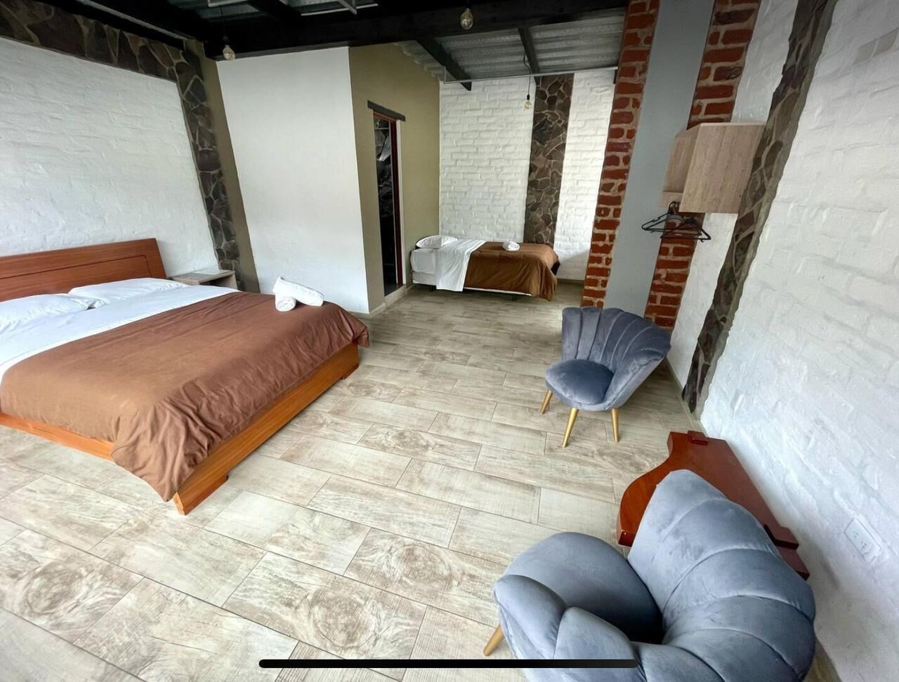 Un dormitorio con una cama grande, una cama más pequeña, dos sillas y una mesita de noche.