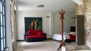 Ein geräumiges Hotelzimmer mit einer großzügigen Badewanne, einem roten Sofa und einem Gemälde an der Wand.