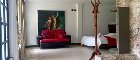 Ein geräumiges Hotelzimmer mit einer großzügigen Badewanne, einem roten Sofa und einem Gemälde an der Wand.