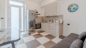 A modern kitchen with a checkered floor, a dining table, and a sofa. - GuestHost - A bright and welcoming 50 square meters apartment, perfect for four people, located on the third floor of a building without an elevator.The property is located in a very quiet area and is close to San Giovanni Bosco Hospital. Thanks to publi (Turin)