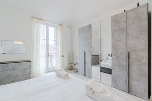 A modern bedroom with a large wardrobe, a bed, a radiator, and a window with curtains. - GuestHost - A bright and welcoming 50 square meters apartment, perfect for four people, located on the third floor of a building without an elevator.The property is located in a very quiet area and is close to San Giovanni Bosco Hospital. Thanks to publi (Turin)