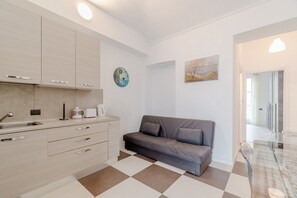 A modern kitchen with a checkered floor, a sofa, and a painting on the wall. - GuestHost - A bright and welcoming 50 square meters apartment, perfect for four people, located on the third floor of a building without an elevator.The property is located in a very quiet area and is close to San Giovanni Bosco Hospital. Thanks to publi (Turin)
