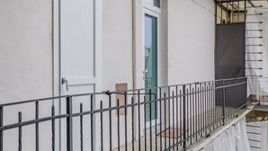 A white building with a metal balcony railing, a green door, and a window. - GuestHost - A bright and welcoming 50 square meters apartment, perfect for four people, located on the third floor of a building without an elevator.The property is located in a very quiet area and is close to San Giovanni Bosco Hospital. Thanks to publi (Turin)