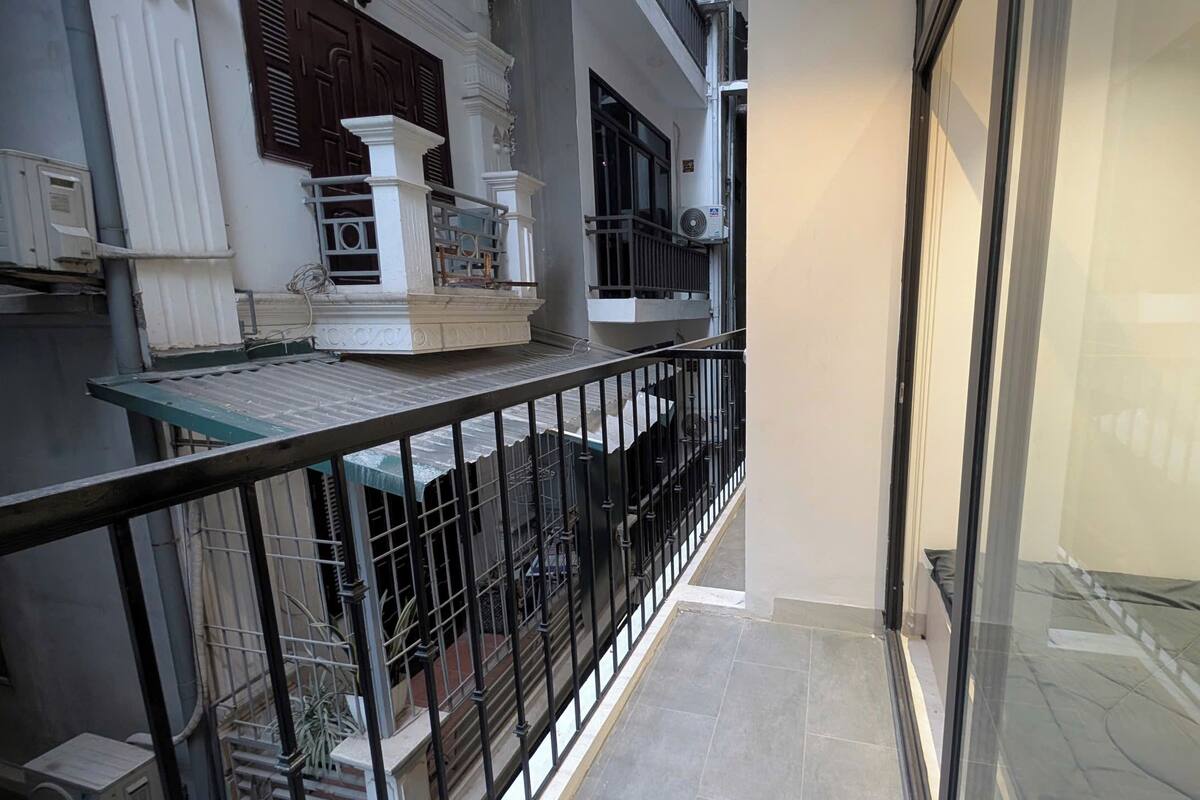 A balcony with a metal railing, a small table, and a potted plant.