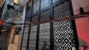 A building facade with a decorative black lattice screen, air conditioning units, and a visible staircase leading to an upper level. - ERA Trung Liet SIGNATURE (Hanoi)