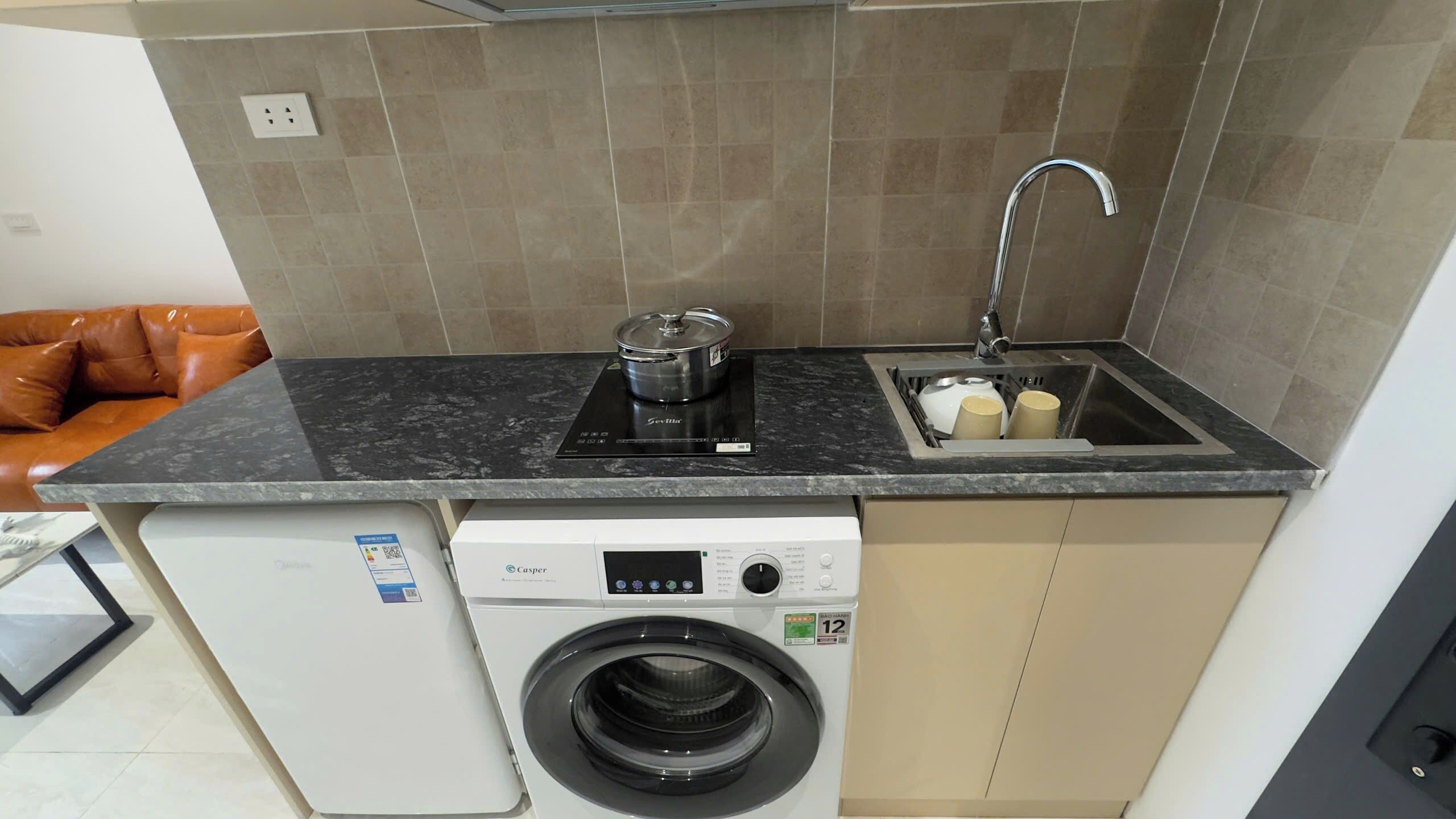 A compact kitchen with a built-in washing machine, a sink, and a countertop.