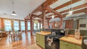 A spacious kitchen with wooden beams, a large stove, and a dining area with a table and chairs. - Loft 40- Game Room- Sleeps 18 (Cleveland)