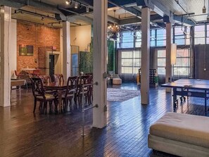 Un grand espace intérieur aménagé avec un billard, des chaises en bois et une table à manger préparée pour le repas.