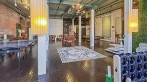 An indoor space with a ping pong table, a patterned rug, and a seating area with chairs and a table. - Loft 40- Game Room- Sleeps 18 (Cleveland)