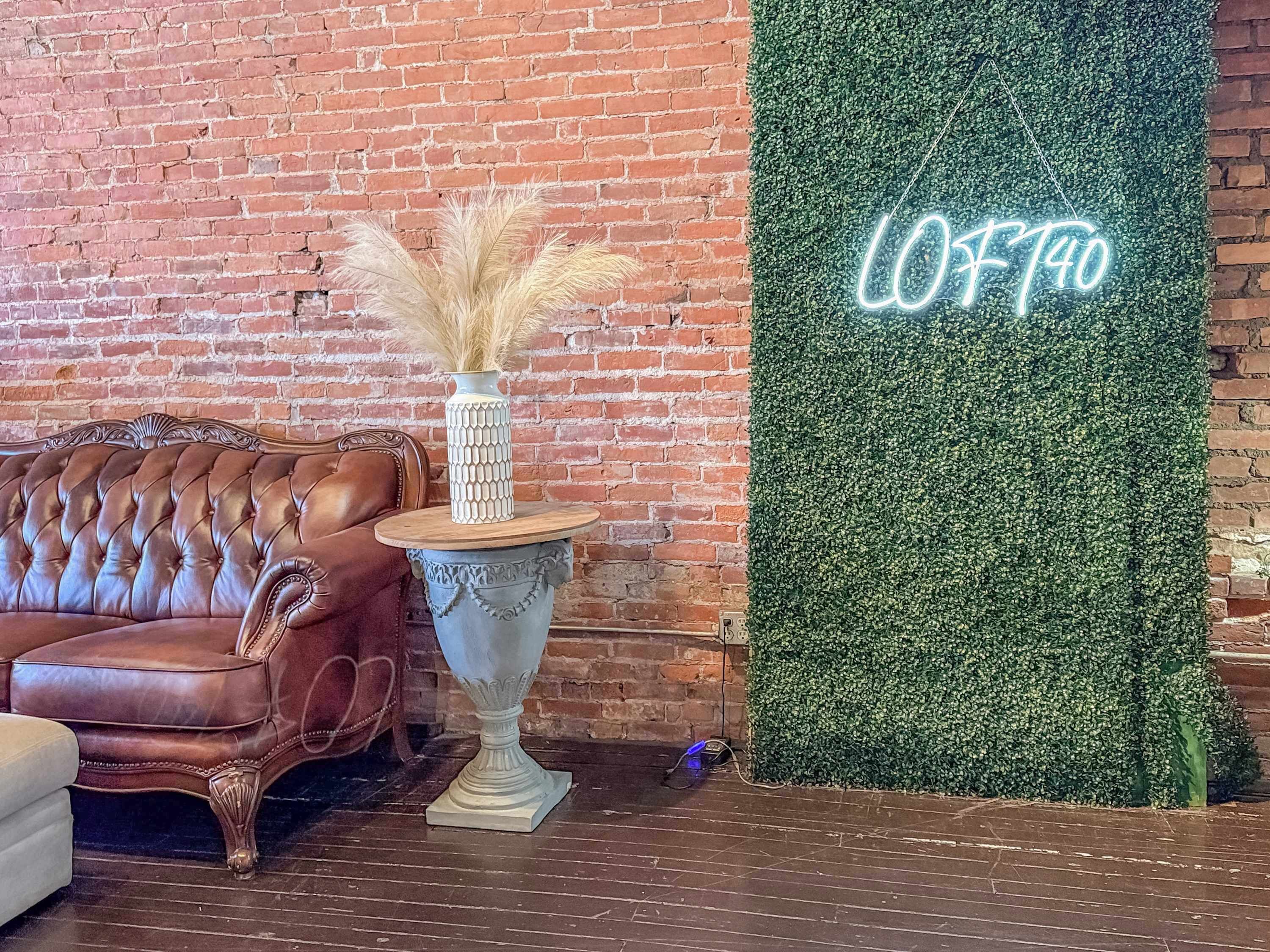 A cozy room with a leather sofa, a decorative vase, and a neon sign reading "LOFT40".